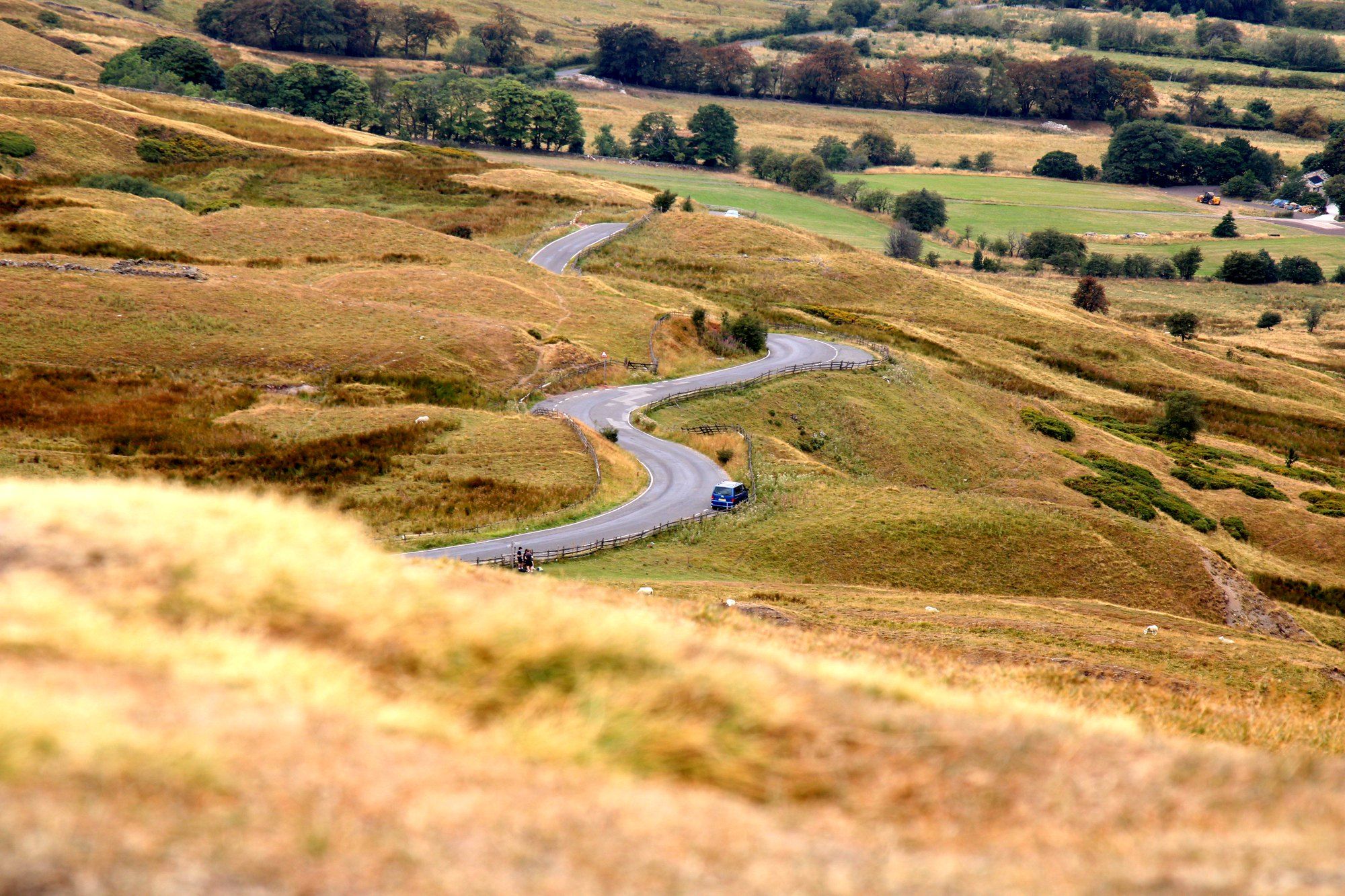A road winding down through the Peak District hills below Mam Tor