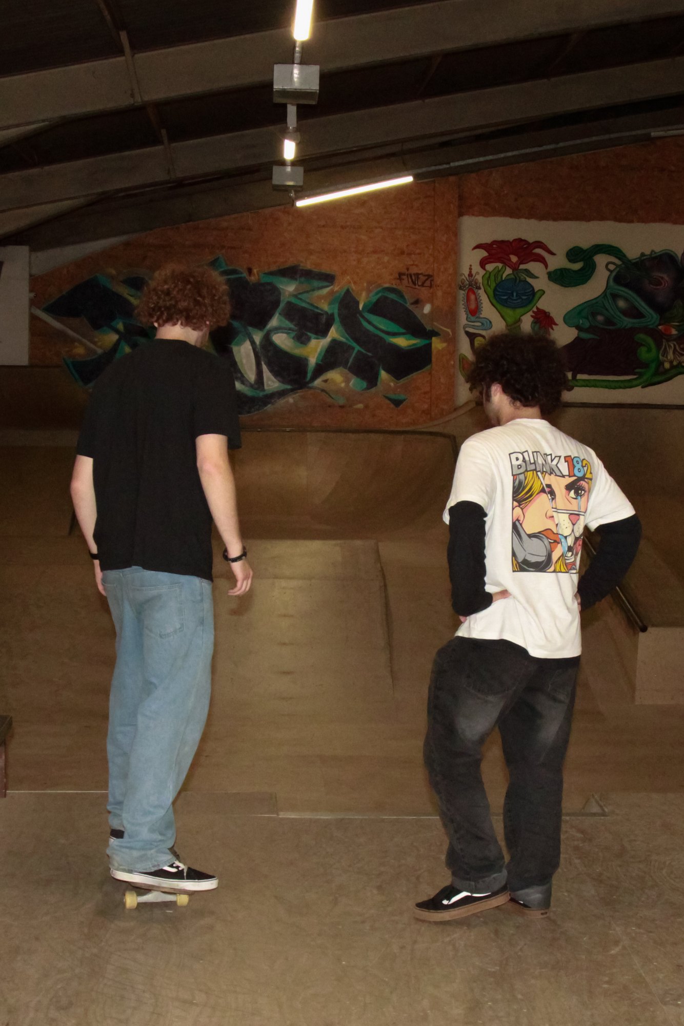 Two skaters looking out across the indoor skate park