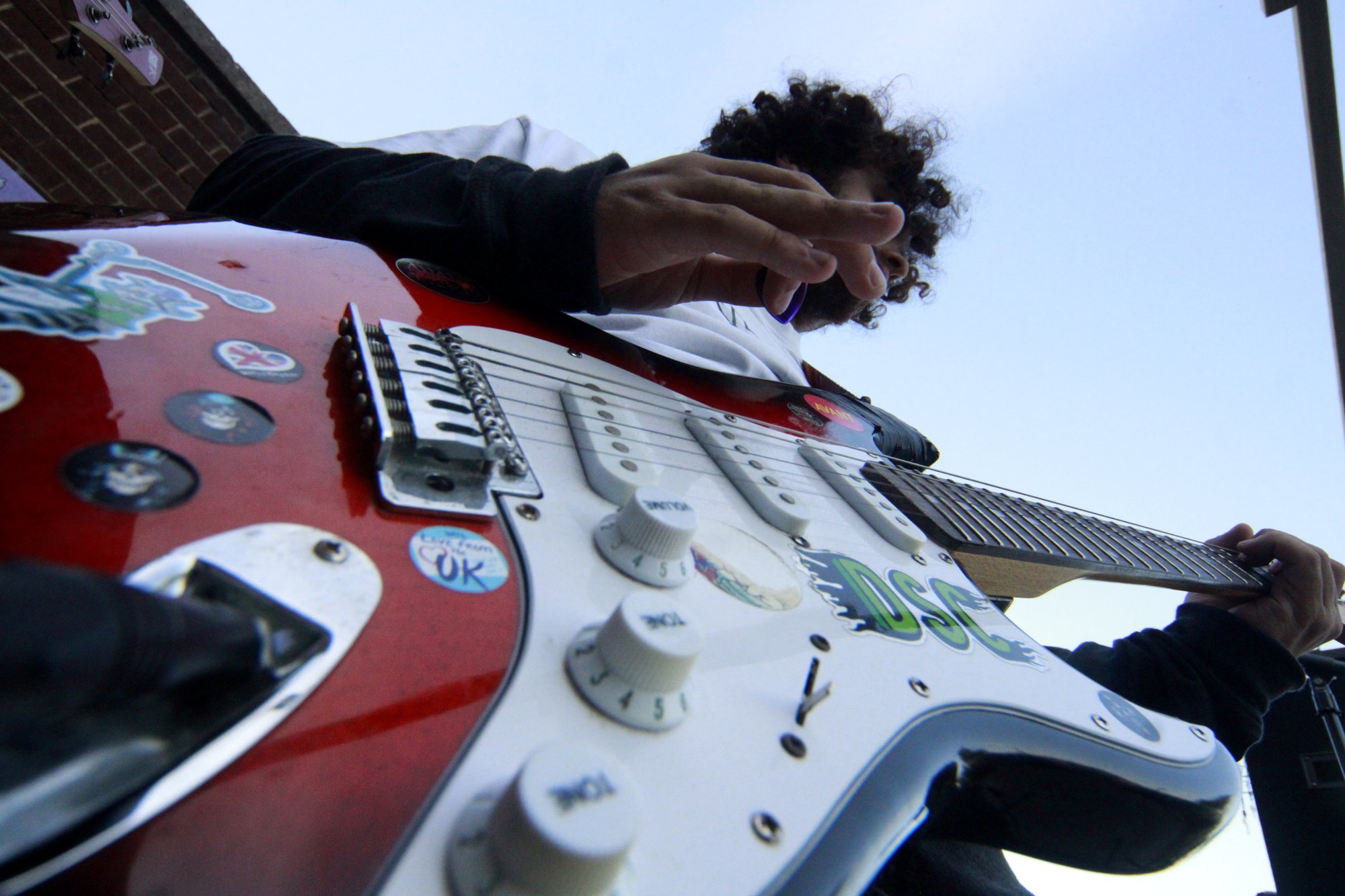 Close-up of a sticker-covered electric guitar being played