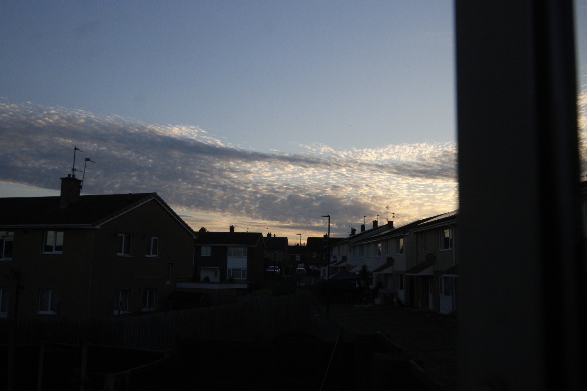 Dusk clouds glowing over a row of rooftops