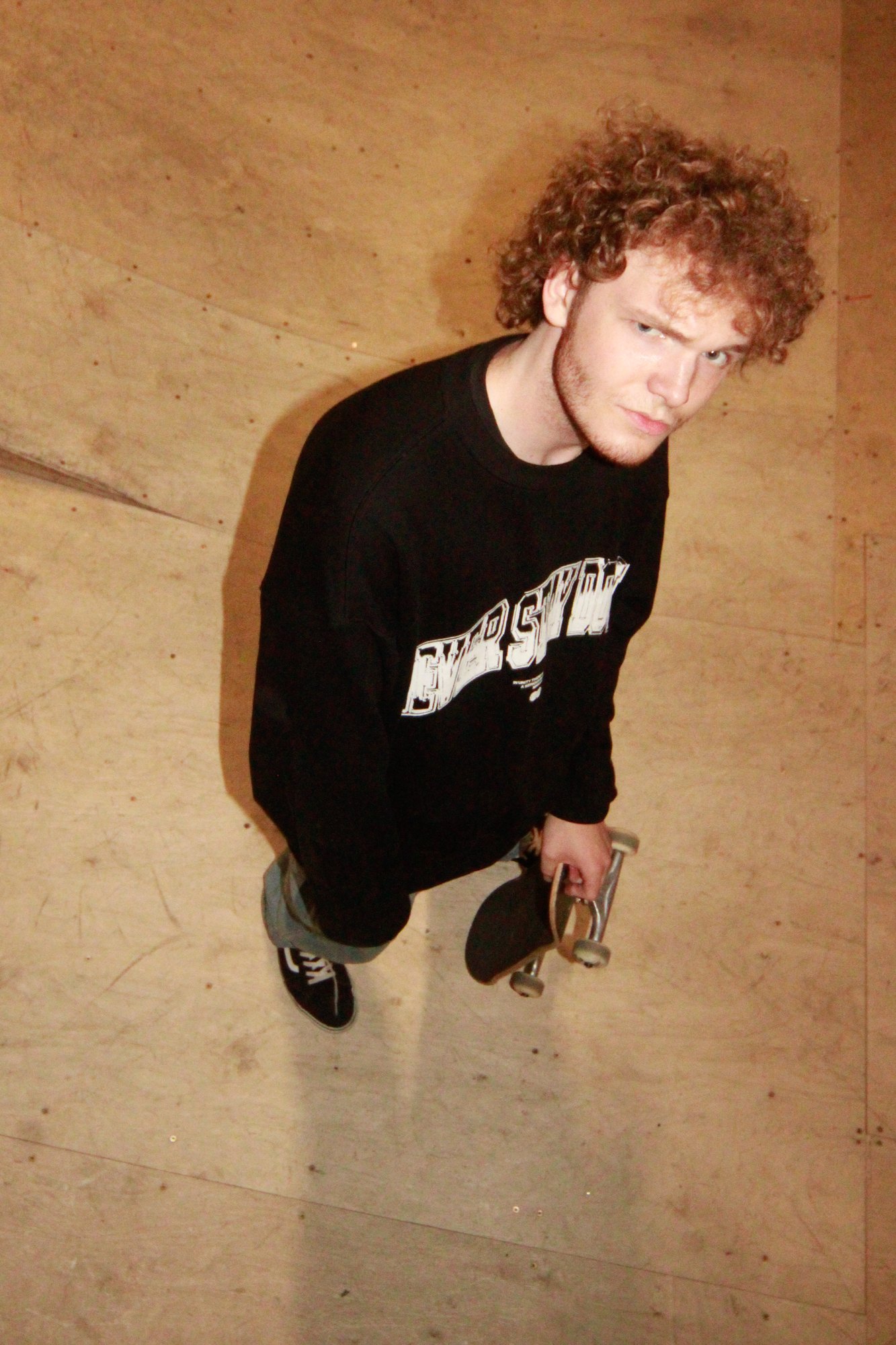 A skater in a black jumper looking up at the camera