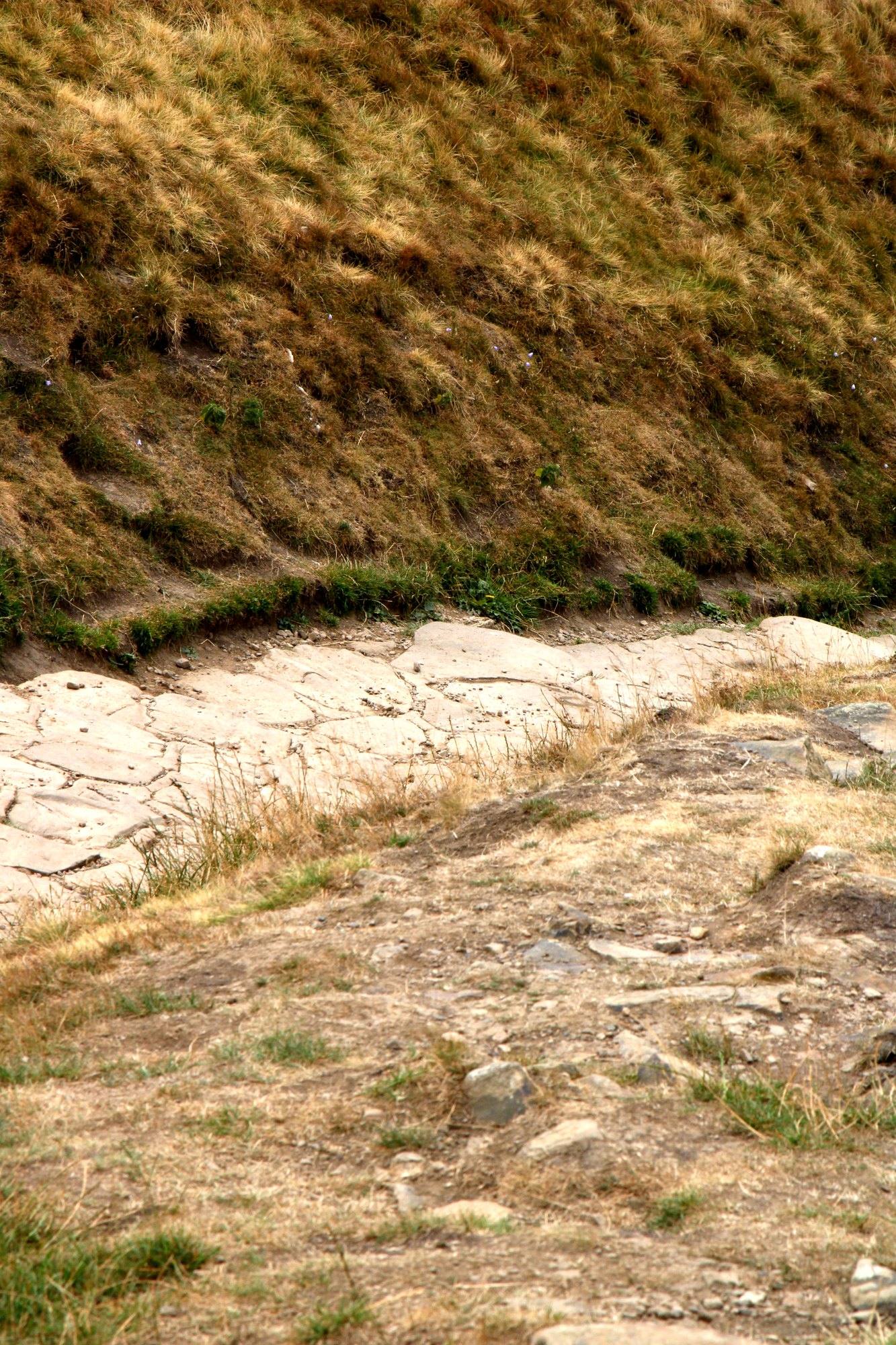 A rocky path through the dry grass on the slope of Mam Tor