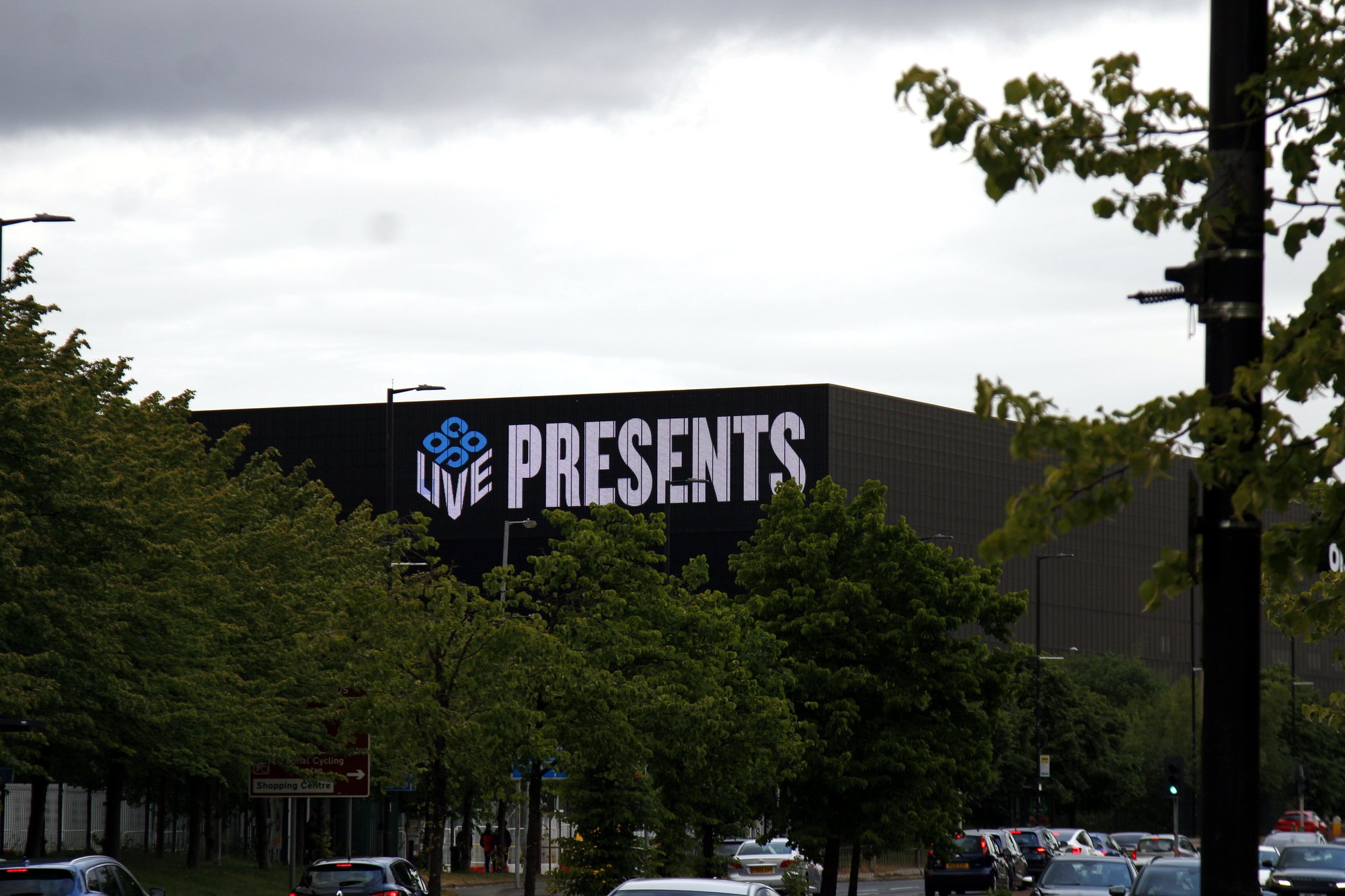 ‘Live presents’ arena signage beyond a row of trees on a grey day